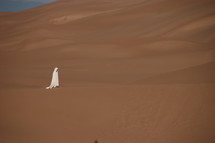 a shrouded man walking in a desert 