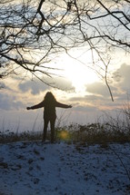 woman standing in the snow with outstretched arms 