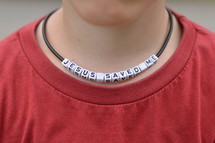JESUS SAVED ME written on beads at a necklace around a kids neck. 