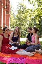 friends sitting on a blanket in the grass for a Bible study at a sunny summer day
