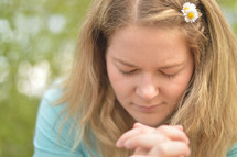 Young blond woman praying outdoors