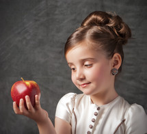 Girl holding and gazing at an apple.