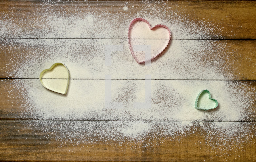 heart shaped cookie cutters on a wood background 