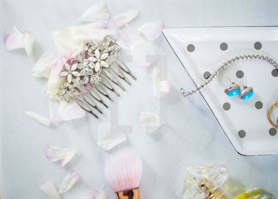 jewel studded hair comb, makeup brush, and flower petals 