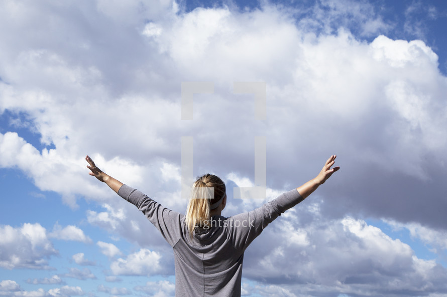 woman standing with raised arms to the sky.