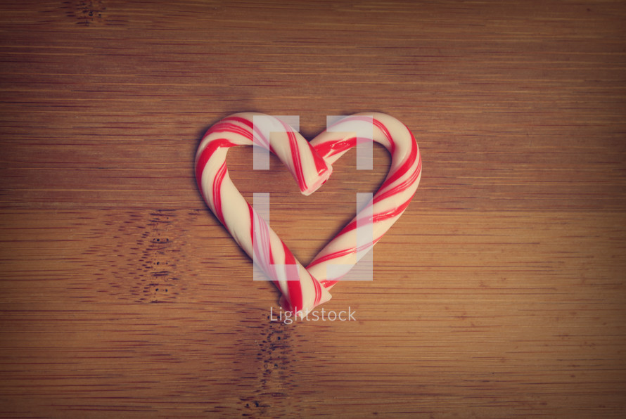 A heart made of peppermint sticks on a wooden table. 