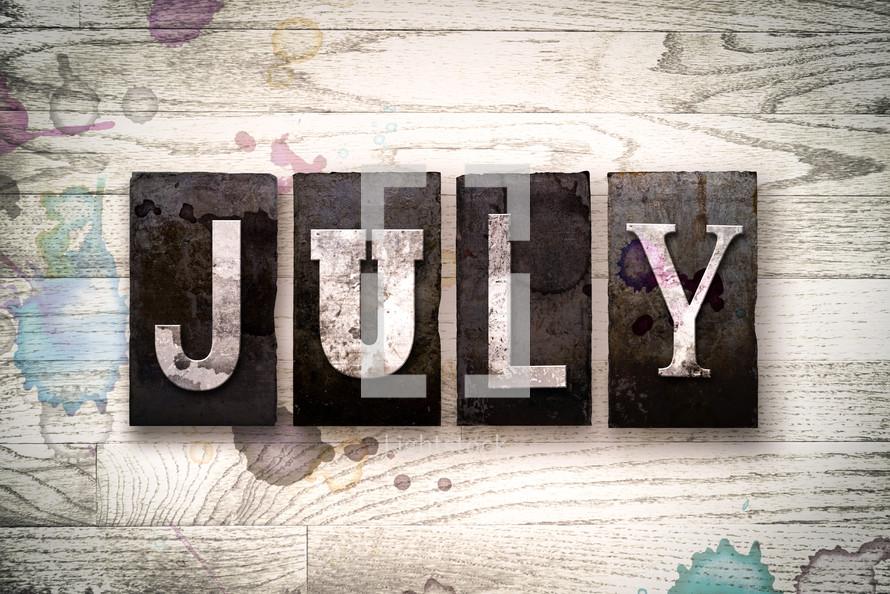 word July on wood background 