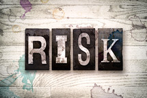 word risk on a white wash wood background 