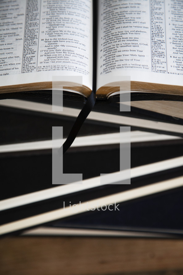 An open Bible on top of a stack of books.