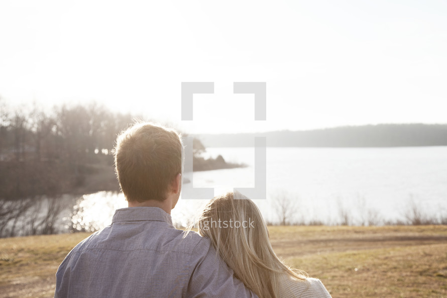 couple standing together by a lake 
