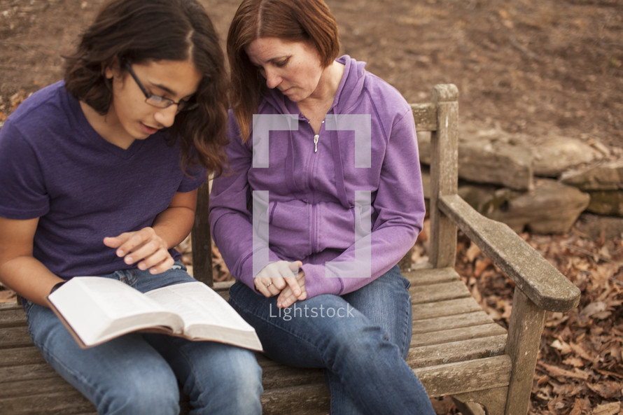 a woman and a young man reading a Bible together 