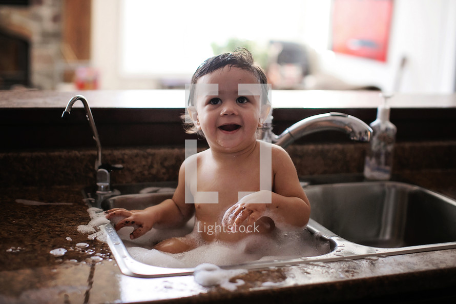 baby taking a bath in a sink 