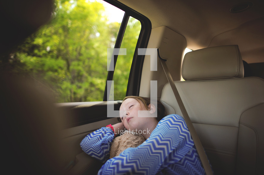 girl child sleeping in the backseat of a car 