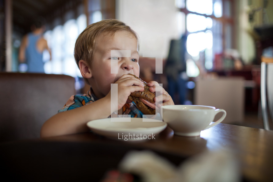 Little boy having sandwich in a cafe