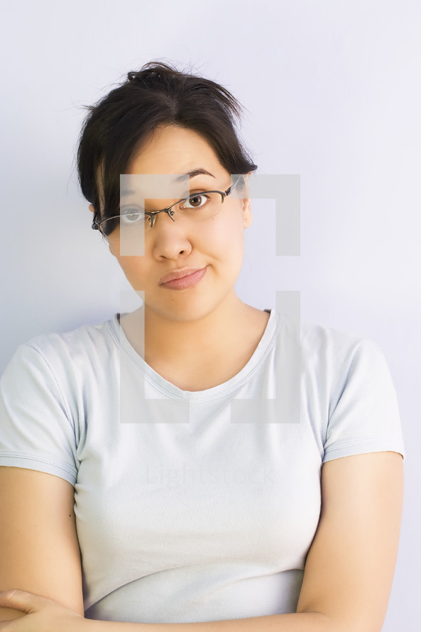 Close up image of skeptical Asian woman wearing glasses with her arms crossed