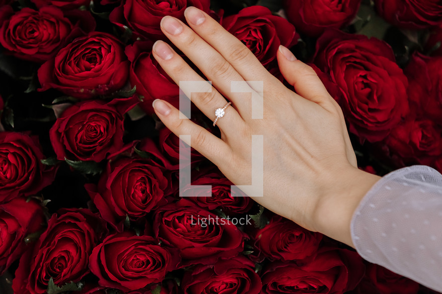 she said yes. close-up of woman hand with engagement rings. Hand of the on the background of the big bouquet of red roses. romantic proposal time.