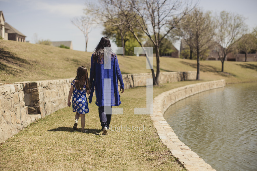 mother and daughter walking holding hands in a park