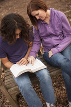 young man and a woman reading a Bible together - mentoring 