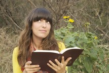 woman reading a Bible outdoors and looking up to God 