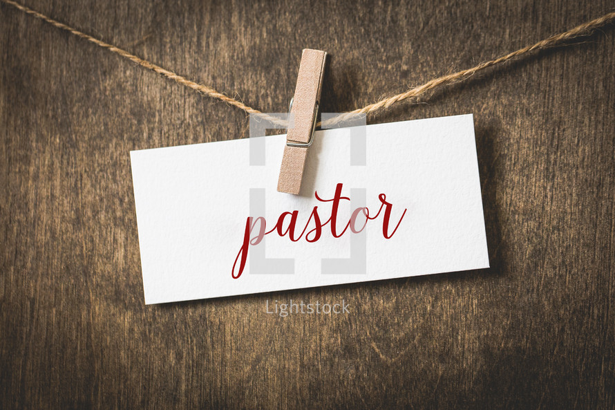 word pastor on white card stock hanging from a clothespin on a clothesline 