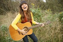 woman laughing playing a guitar 