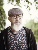 an elderly man with a beard wearing a hat and glasses 