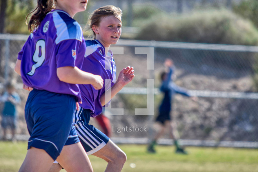 girls running on a soccer field 