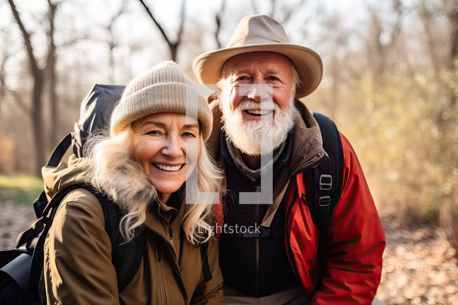 Happy senior couple hiking in the countryside, looking at camera and smiling.