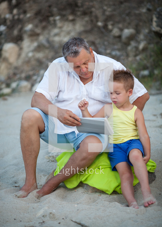 Grandfather and grandchild using pad on the beach