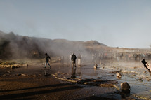tourists gathered around steam rising from the ground 