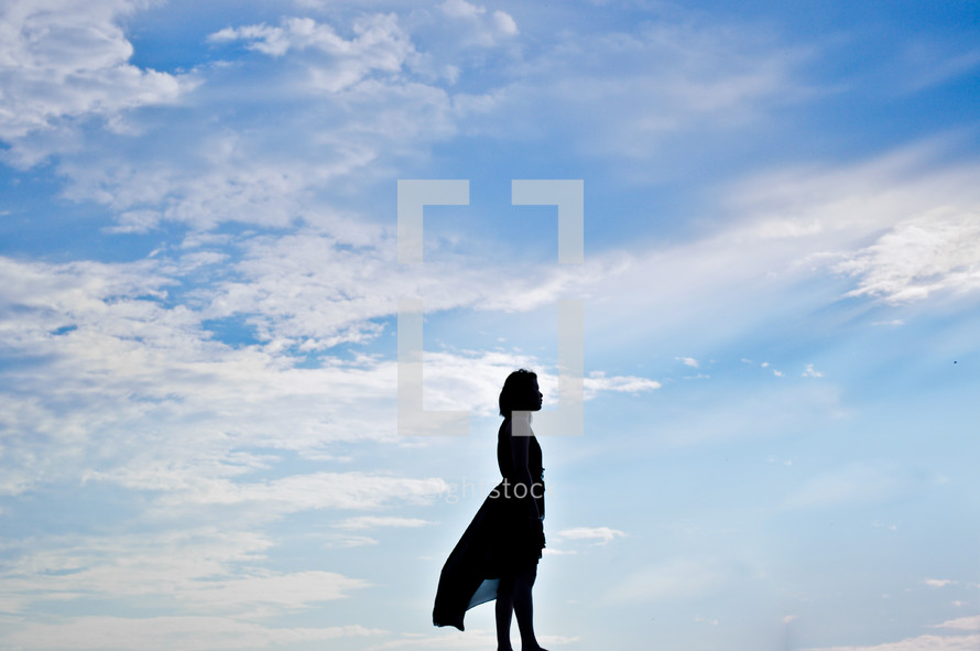 a silhouette of a woman standing with open arms 