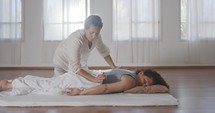 Shiatsu treatment. Masseuse pressing and massaging the back and the shoulders of woman
