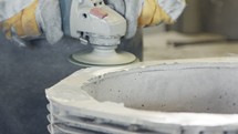 Clouse up of a worker's hands polishing a metal casting part using a grinder