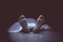 feet from a dead body covered with a white sheet 