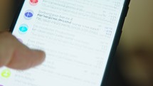 close up of hand browsing through emails on a smartphone screen