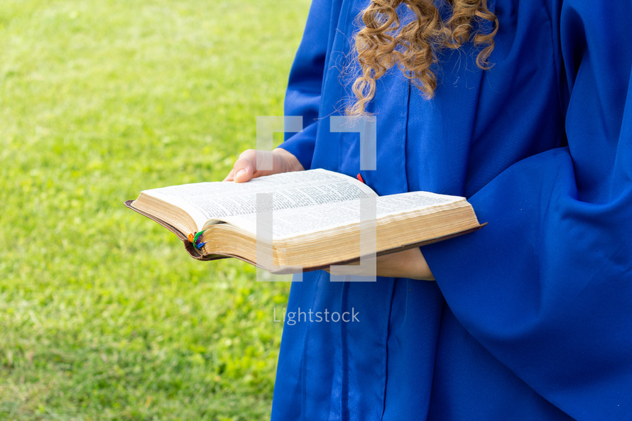 portrait of a female graduate outdoors holding a Bible 