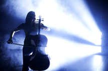 woman in a spot light playing a cello 