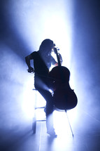 woman playing a cello under a spot light on stage