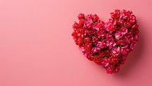 Heart made of red flowers on pink background. Valentines day concept