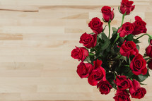 Red roses on a wood grain table.