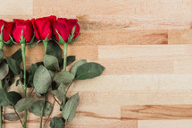 red long stem roses on wood