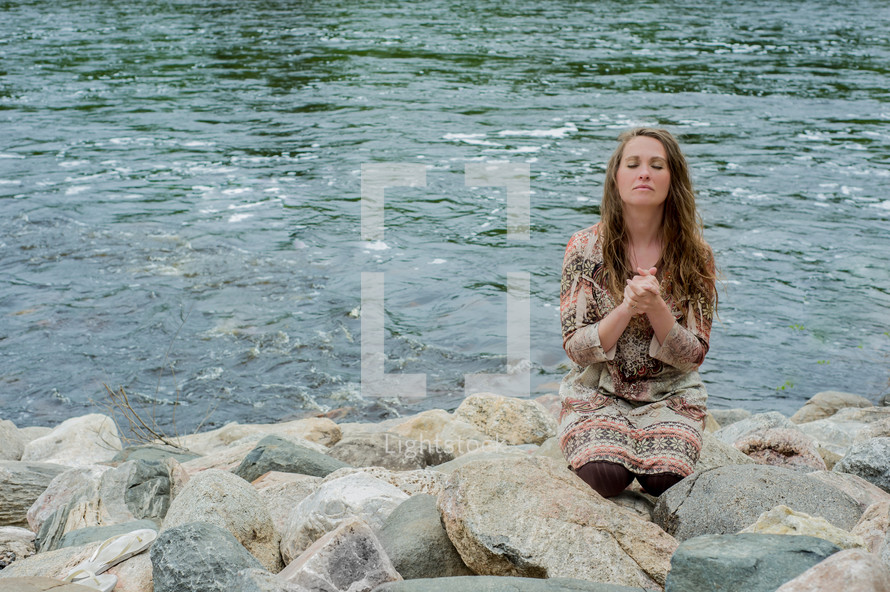 woman in prayer at a rocky shore