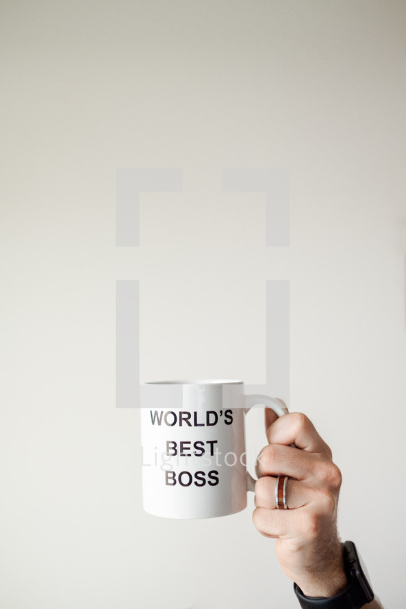 person holding up World's Best Boss mug 
