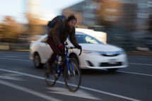 a man riding a bicycle on a road near passing cars 