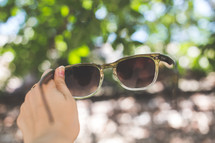 woman holding up sunglasses 