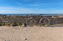 bike leaning against a stone wall on a beach 