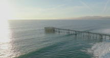 Fishing pier sticks out over the pacific ocean at beach in Venice, Florida. 