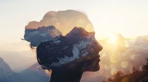 A close-up of a womans face with a backdrop of towering mountains in the distance, creating a striking contrast between the delicate features of the woman and the rugged terrain.