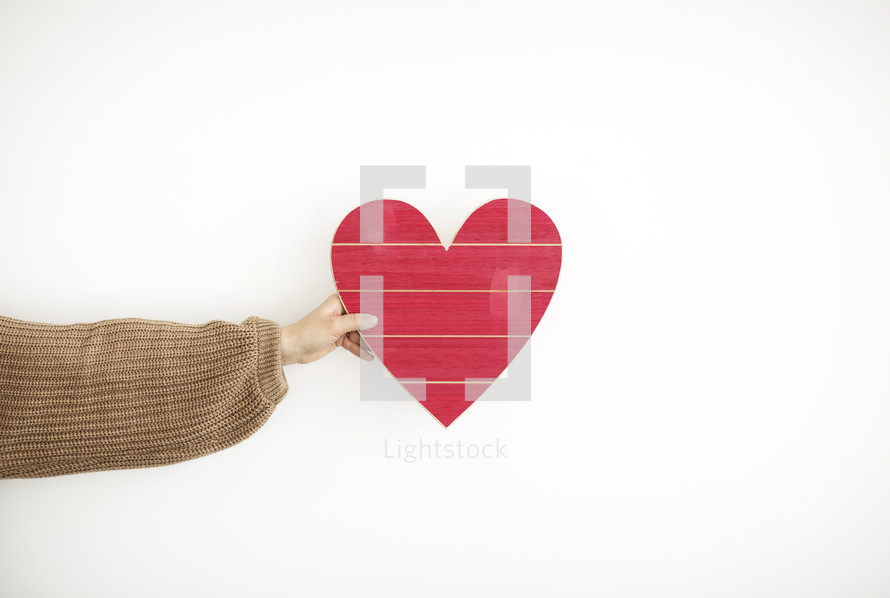 arm holding out a wooden Valentine's Day heart 