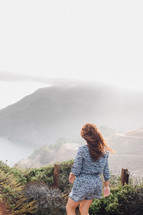 a woman walking on a foggy mountaintop 